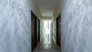 Un pasillo largo y estrecho con puertas a ambos lados, que conduce a una habitación luminosa al final.