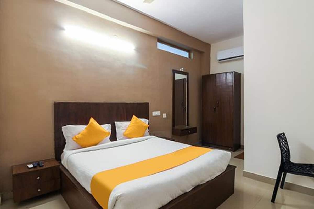 A hotel room with a large bed, a wardrobe, a desk, and a chair.