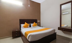 A bedroom with a large bed, two bedside tables, a mirror, and a wall-mounted air conditioning unit. - Fabexpress R Inn (Hyderabad)