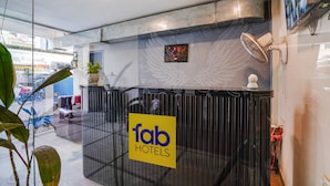 A reception area with a glass partition, a sign for 'fab hotels', and a mounted fan.