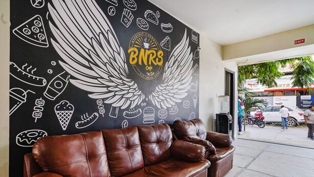 A brown leather couch in front of a wall with a mural featuring food and drink icons, and a sign that reads "BNRS Cafe".
