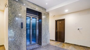 A modern elevator with a digital display, a marble wall, and a wooden door.