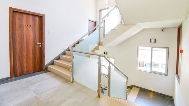 A staircase with a glass railing, a wooden door, and a window. - Fabhotel Prime Kantara (Mawal)