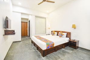 A hotel room with a bed, a nightstand, a TV, and a ceiling fan.