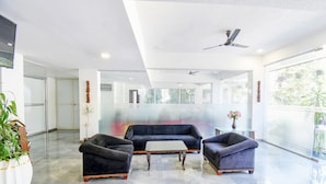 A modern lobby with a black sofa, two armchairs, a coffee table, and a ceiling fan. - Fabhotel Prime Kantara (Mawal)