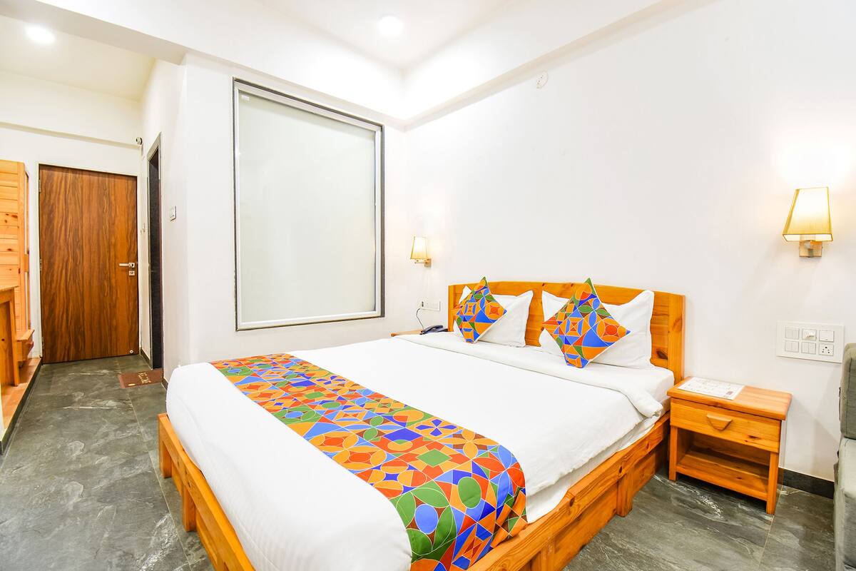 A hotel room with a bed, wooden nightstand, and a wardrobe.
