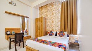 A hotel room with a bed, a desk with a chair, a wardrobe, and a bathroom area. - Fabhotel Grand Vista Inn (Bengaluru)