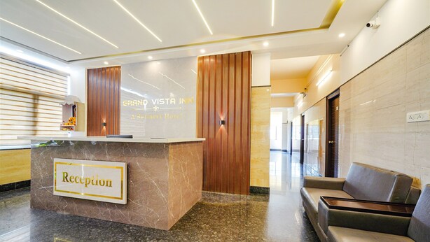 A reception area with a marble counter, a sign reading "Reception," and a seating area with a sofa. - Fabhotel Grand Vista Inn (Bengaluru)