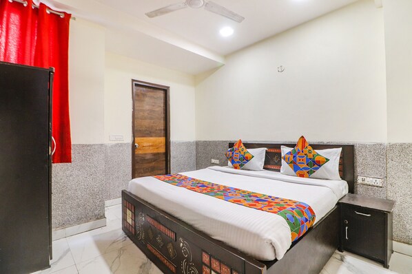 A bedroom with a bed, a nightstand, a wardrobe, and a door. - Fabexpress King Stay (New Delhi)