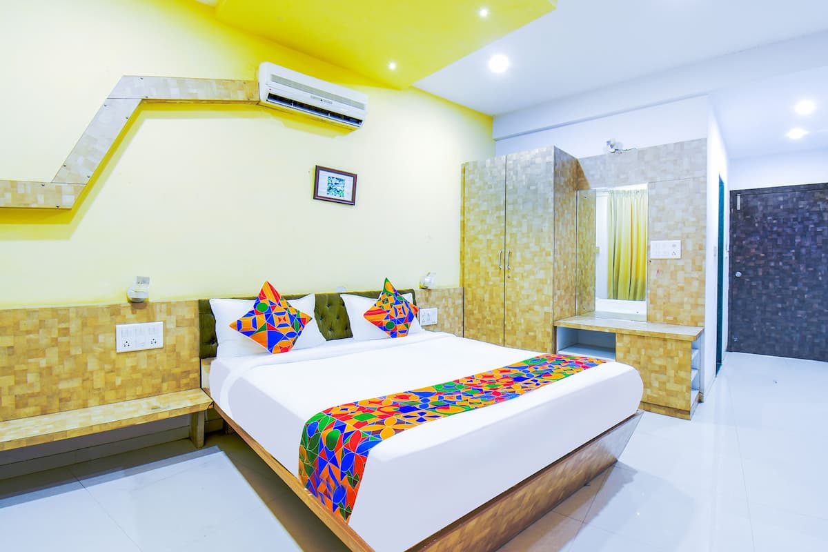 Una habitación de hotel con cama, un banco, un tocador y un espejo.