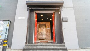 Entrada de hotel com parede de mármore, porta com a placa 'Concept?' e a placa '23 PH ROAD PERIMET'.