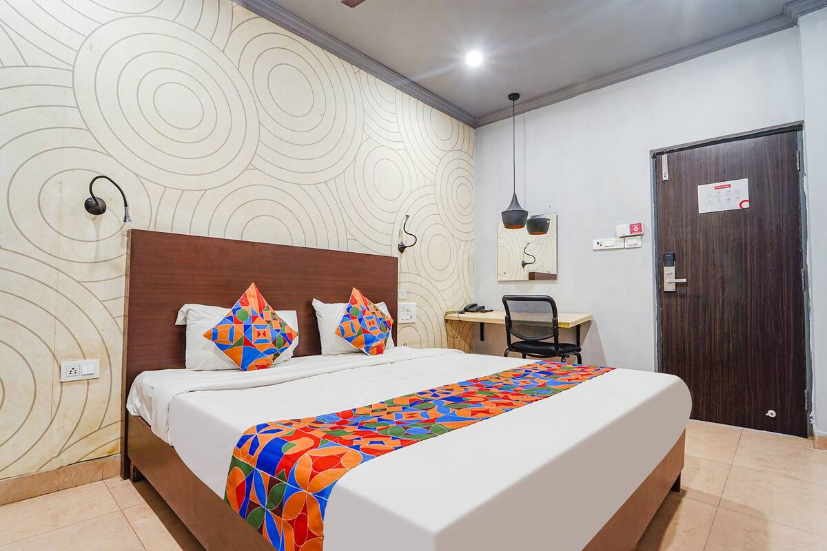 A hotel room with a large bed, a desk, and a chair.