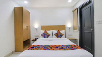 A neatly arranged bedroom with a bed, a wardrobe, a bedside table, and a door.