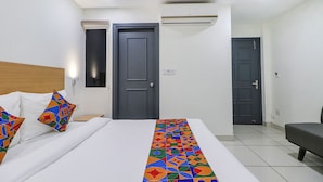 Una habitación de hotel con una cama, una mesita de noche, una silla y dos puertas.
