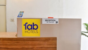 Una mesa de recepción con un cartel de 'fab hotels', un cartel de 'recepción' y un código QR.
