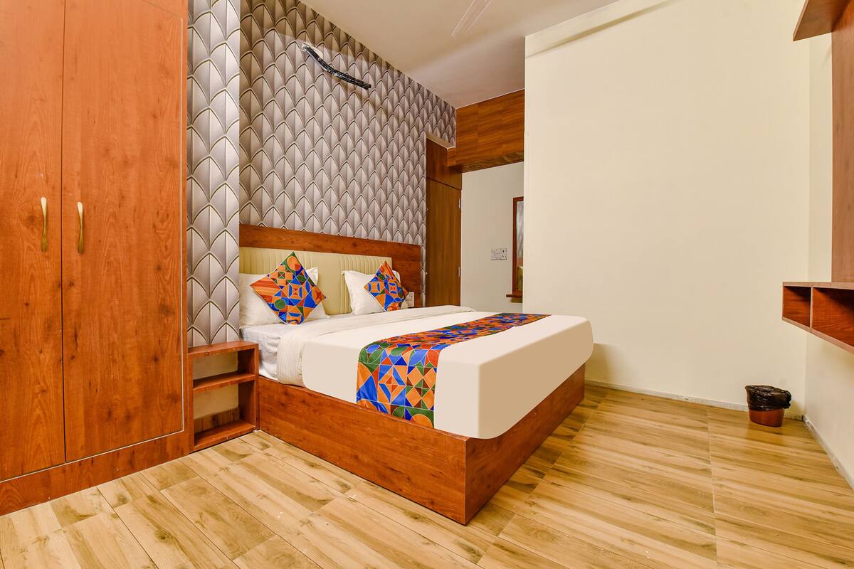 Un dormitorio con estructura de cama de madera, cabecera con diseño geométrico y armario de madera.