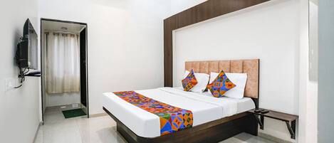 A modern hotel room with a large bed, a TV, and an air conditioning unit.