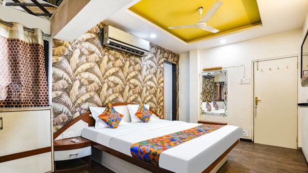 A bedroom with a bed, a wardrobe, a ceiling fan, an air conditioning unit, and a mirror.
