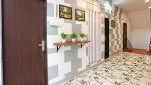 A hallway with a checkered wall pattern, a wooden door labeled '108', and a shelf with potted plants.