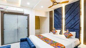 A hotel room with a large bed, a ceiling fan, a wardrobe, and a bathroom visible through an open door.