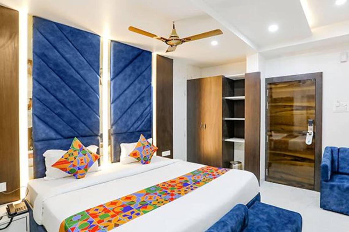 A modern hotel room with a large bed, a ceiling fan, and a blue sofa.