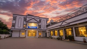 A hotel with a modern facade, a sign reading "fabHOTELS," and a spacious courtyard.