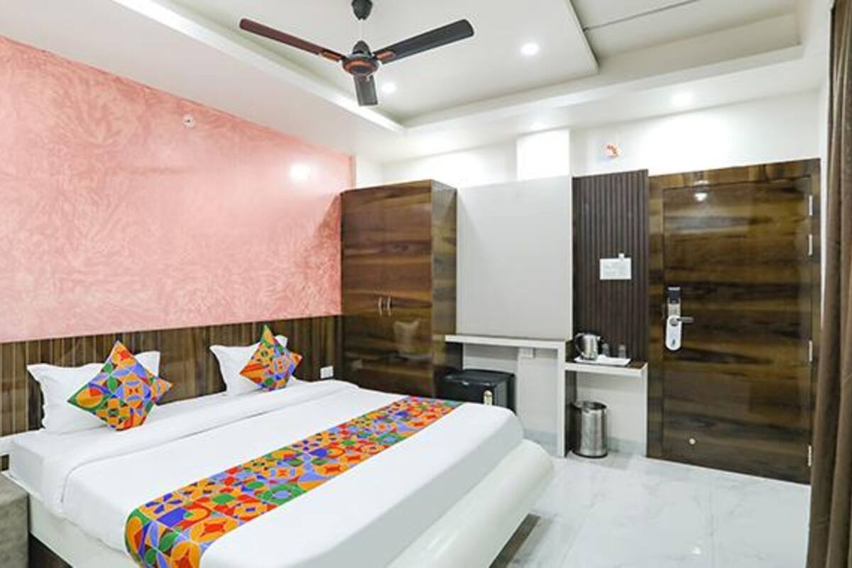 A modern hotel room with a large bed, a ceiling fan, a vanity with a mirror, and a small desk.