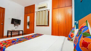 A bedroom with a bed, wooden wardrobe, a television on a stand, and an air conditioning unit. - FabHotel Harma Residency - near Velachery Railway station (Chennai)