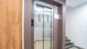An elevator with a digital display, a sign above it, and a staircase to the right. - Fabhotel Prime Palace View (Vadodara)