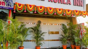 A hotel named "KURLA INN" with a closed shutter, potted plants, and a garland of flowers. - Fabexpress Kurla Inn (Mumbai)