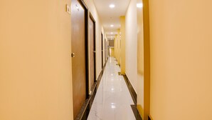 A long, narrow hallway with doors on one side and a tiled floor. - Fabexpress Kurla Inn (Mumbai)