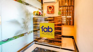 A reception area with a 'fab hotels' sign, a wooden reception desk, a wall-mounted air conditioner, and a small shrine with flowers. - Fabexpress Kurla Inn (Mumbai)