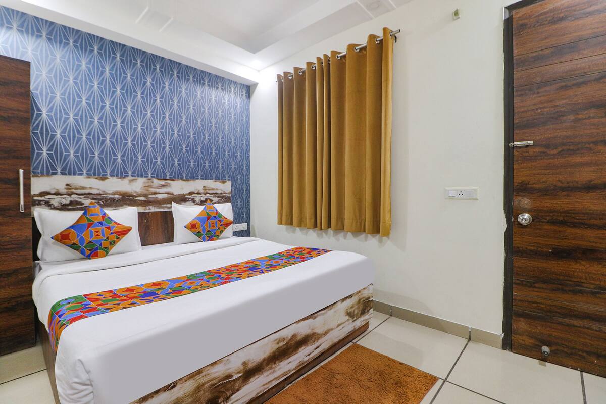 A bedroom with a bed, a patterned wall, a curtain, and a wooden door.
