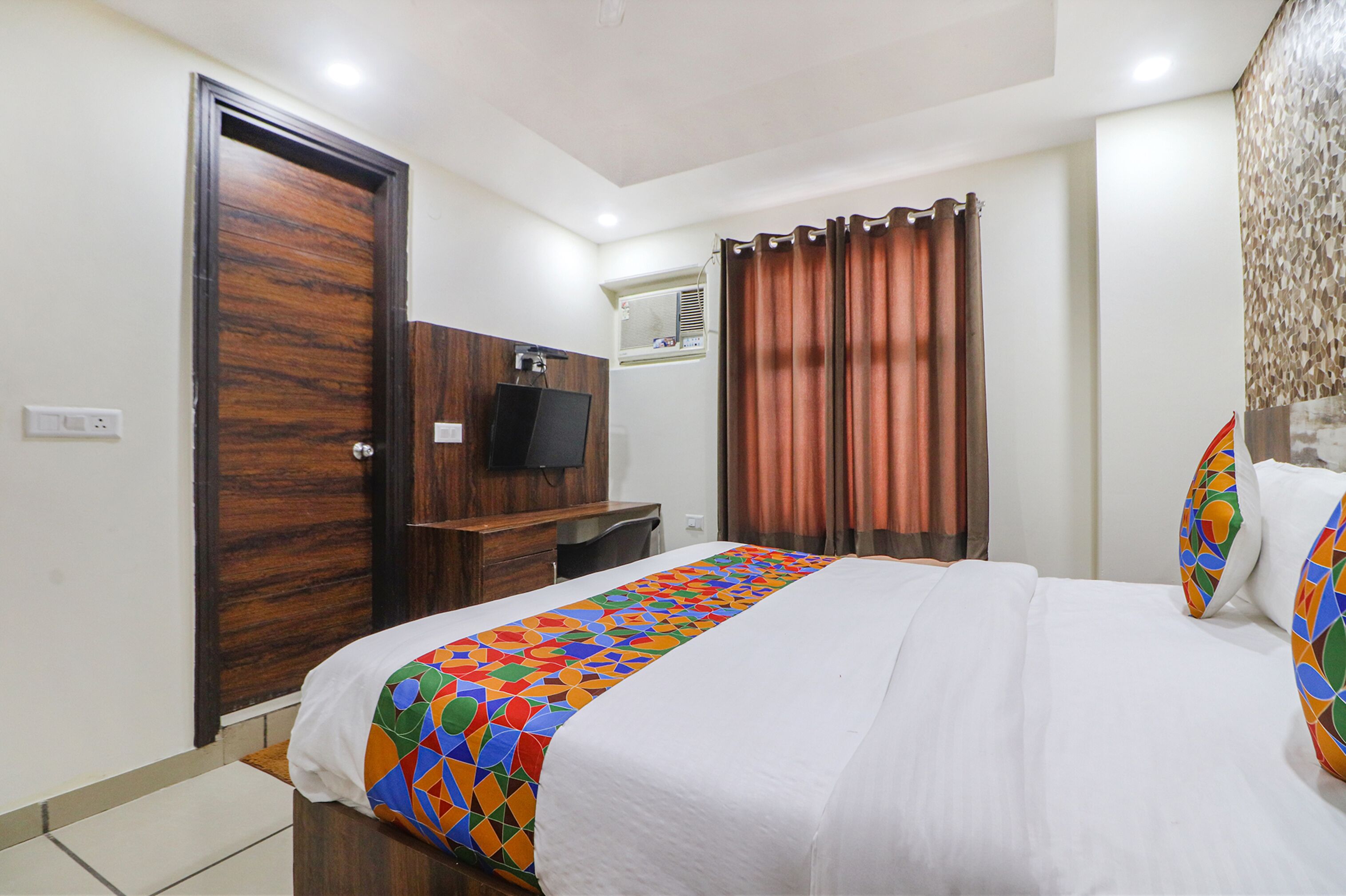 A hotel room with a bed, a TV, a desk, and a wardrobe.
