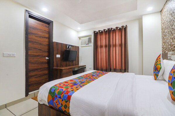 A hotel room with a bed, a TV, a desk, and a wardrobe. - Fabhotel Empire Suites (New Delhi)