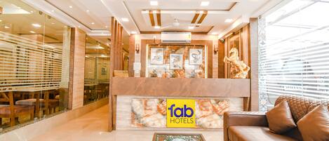 A hotel reception area with a marble counter, a sofa, and a decorative coffee table.