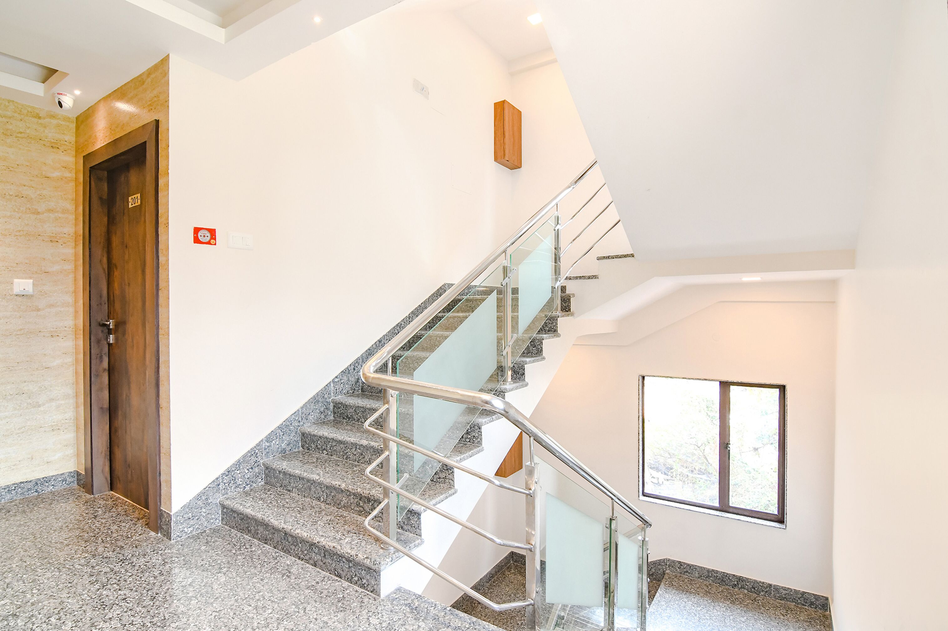 A modern interior with a granite staircase, a wooden door, and a window.