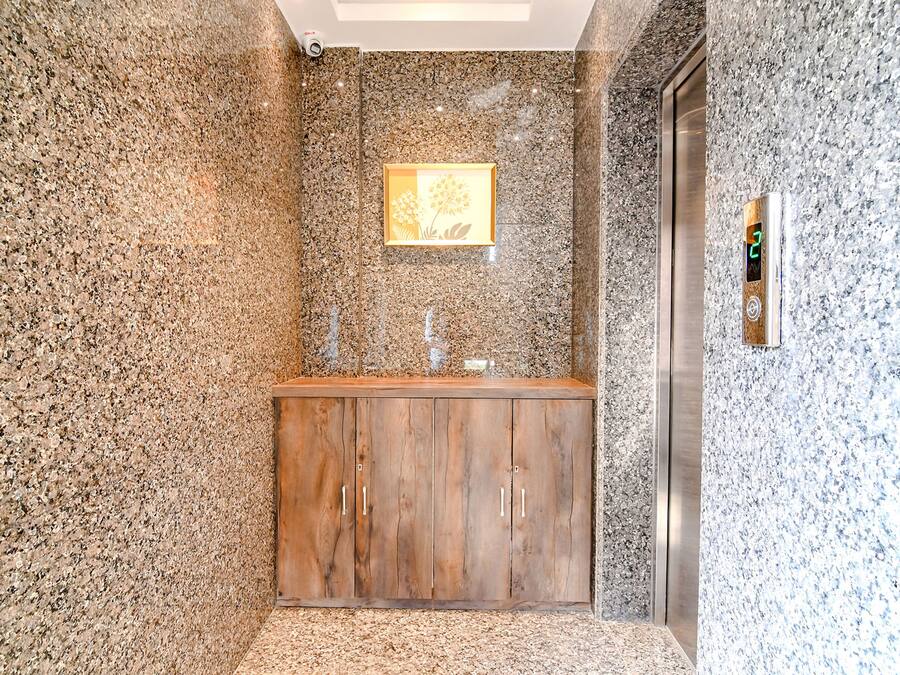 A modern bathroom with a wooden vanity, granite walls, and a framed artwork above the mirror.