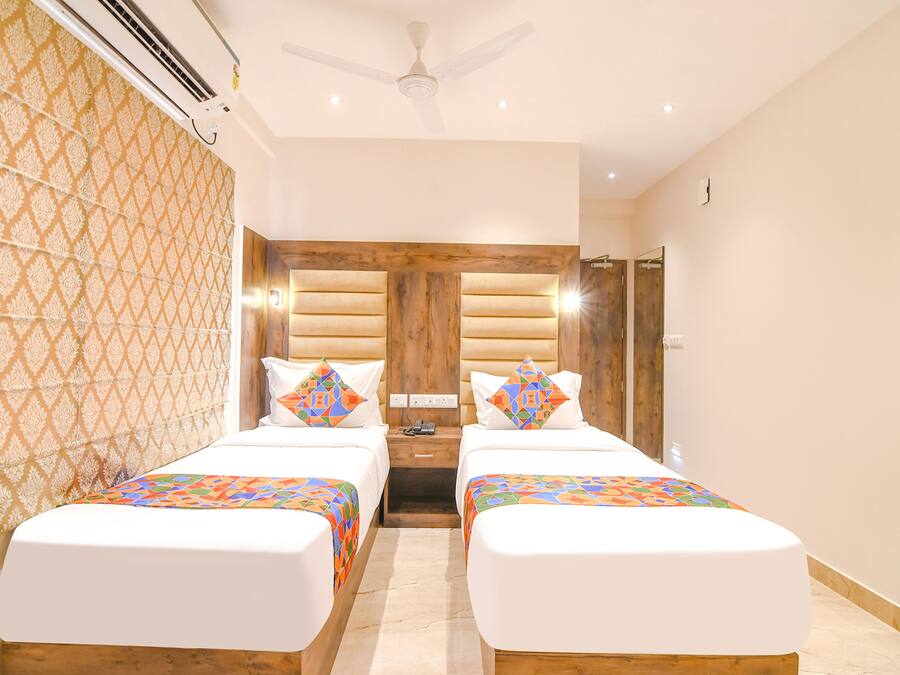 A hotel room with two beds, a wooden headboard, a ceiling fan, and a patterned wall.