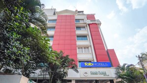 A hotel with a prominent red and white facade, a visible sign for 'Tab Hotels', and a sign for 'Seven Olives Hotels'. - Fabhotel Seven Olives (Bengaluru)