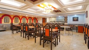A spacious dining area with multiple tables and chairs, high ceilings with skylights, and decorative wall arches. - Fabhotel Seven Olives (Bengaluru)