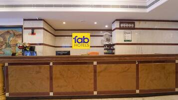 A reception area with a marble counter, a 'fab hotels' sign, a clock, and a fan.
