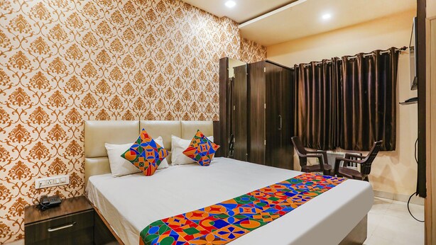 A hotel room with a large bed, a nightstand, a desk, and a wardrobe. - Fabhotel Bala Ji Inn (Varanasi)