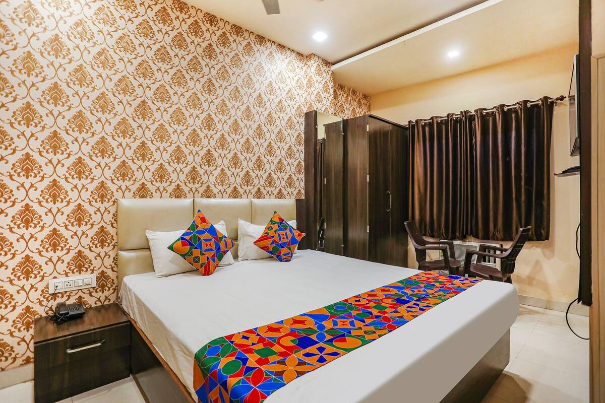 A hotel room with a large bed, a nightstand, a desk, and a wardrobe.