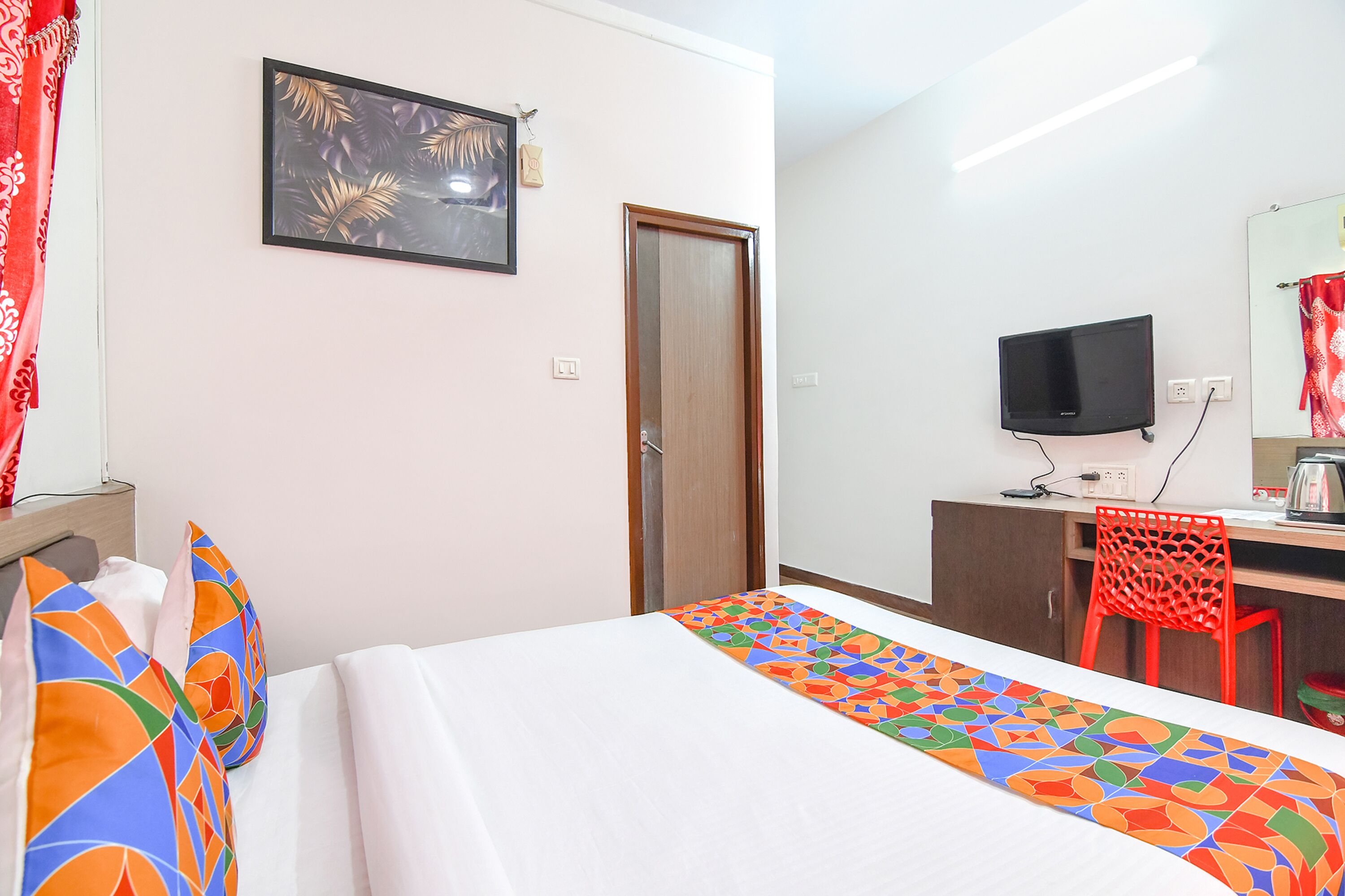 A hotel room with a bed, a desk, a television, and a chair.