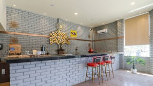 A reception area with a brick wall, a 'fab hotels' sign, a reception desk, and three red bar stools. - Fabhotel Saalt Bandhan Resort (Pashchimi Muzaffarpur)