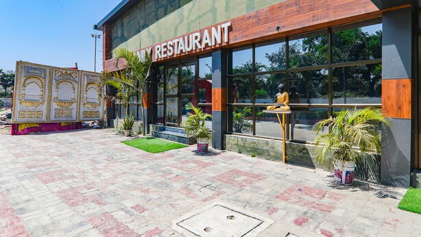 A restaurant with a modern facade, large windows, and potted plants in the entrance area. - Fabhotel Saalt Bandhan Resort (Pashchimi Muzaffarpur)