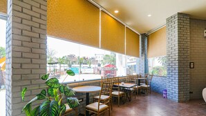 A restaurant with brick walls, large windows, and indoor plants. - Fabhotel Saalt Bandhan Resort (Pashchimi Muzaffarpur)