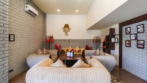 A modern living room with a sofa set, a decorative elephant headpiece on the wall, and a brick wall with an air conditioning unit. - Fabhotel Saalt Bandhan Resort (Pashchimi Muzaffarpur)