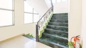Un escalier avec une rampe, un extincteur et de grandes fenêtres.